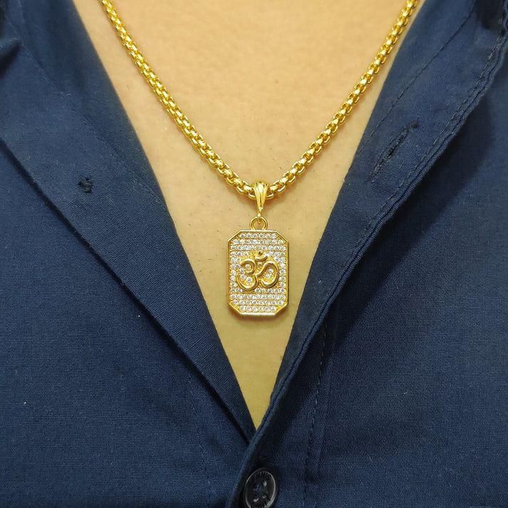 Gold necklace with a pendant on a person wearing a navy blue shirt.