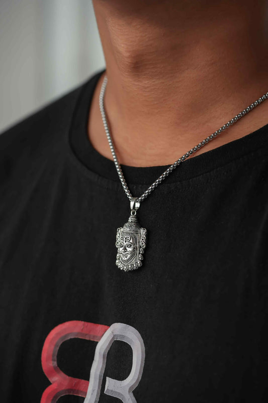 Person wearing a black shirt with a red and gray design, featuring a silver necklace with a pendant.