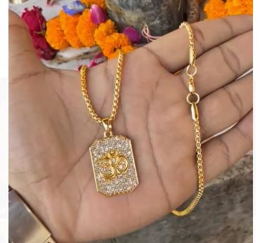 Gold necklace with a pendant on a hand, decorated with flowers in the background